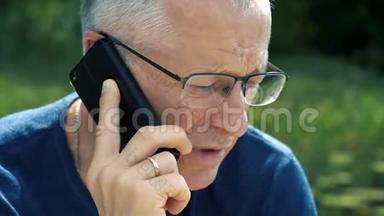 一个穿着蓝色t恤和眼镜、头发花白、严肃认真的男人，坐在船上严格地打电话